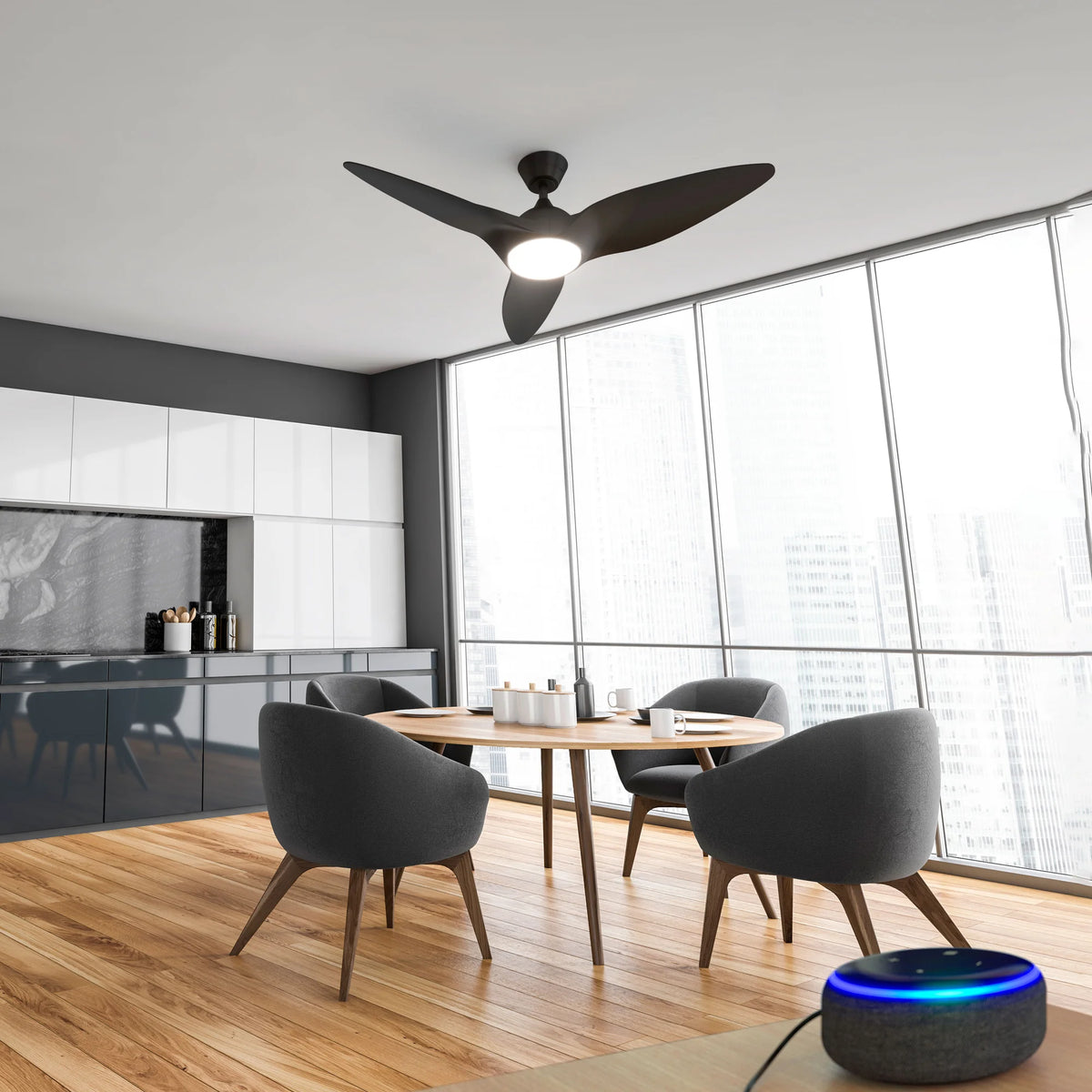Monarc Smart Ceiling Fan installed in a modern kitchen with natural light, wood flooring, and a round dining table. An Alexa smart speaker sits on the nearby counter.